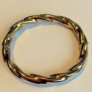 Gold colored metal twisted bracelet with flip clasp for security